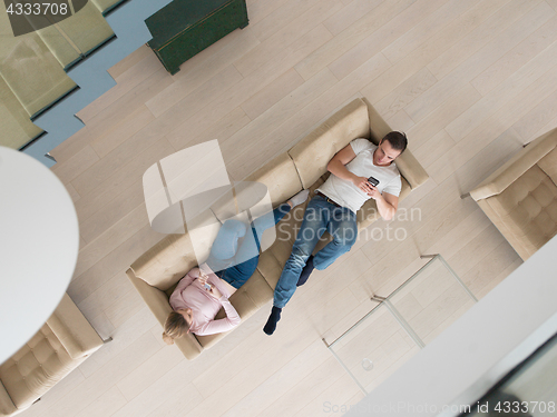 Image of couple on sofa using mobile phones top view