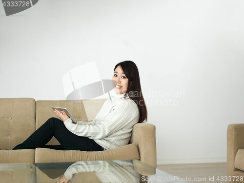 Image of asian woman using Digital Tablet on sofa