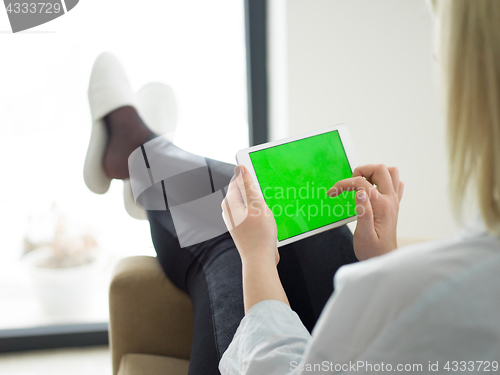 Image of young woman using tablet computer in front of fireplace