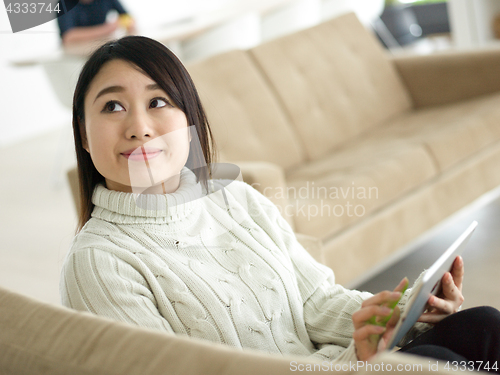 Image of asian woman using Digital Tablet on sofa