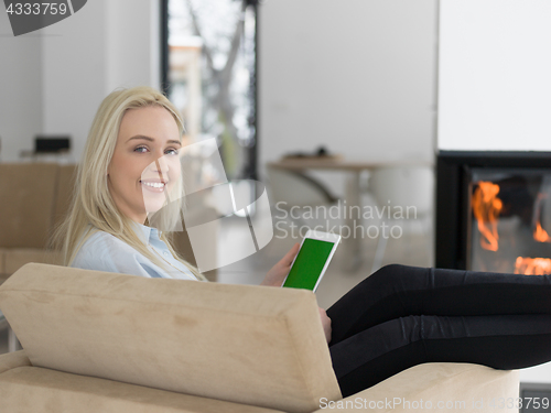 Image of young woman using tablet computer in front of fireplace