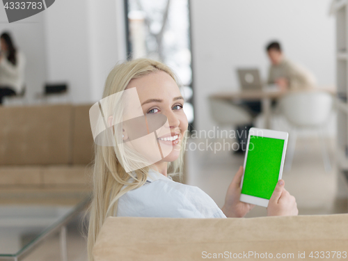 Image of young woman using tablet computer in front of fireplace