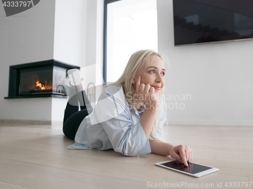 Image of woman using tablet computer in front of fireplace