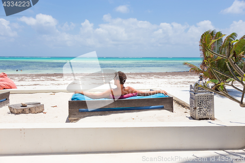 Image of Relaxed man in luxury lounger enjoying summer vacations on beautiful beach.