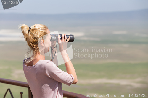 Image of Female tourist looking through binoculars on African safari in Ngorongoro crater consrvation area, Tanzania, Afrika.
