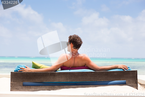 Image of Relaxed man in luxury lounger enjoying summer vacations on beautiful beach.