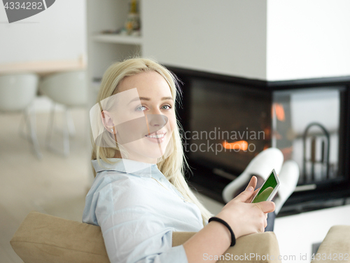 Image of young woman using tablet computer in front of fireplace