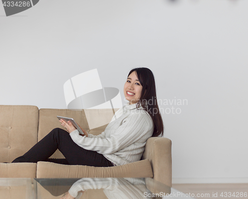 Image of asian woman using Digital Tablet on sofa