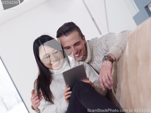 Image of multiethnic couple at home using tablet computers