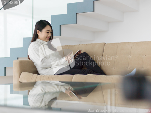 Image of asian woman using Digital Tablet on sofa