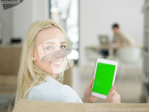 Image of young woman using tablet computer in front of fireplace