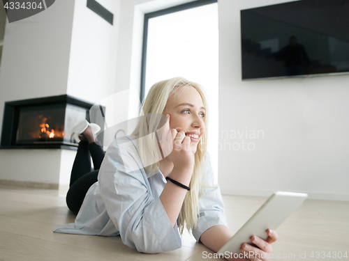 Image of woman using tablet computer in front of fireplace