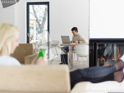 Image of young woman using tablet computer in front of fireplace