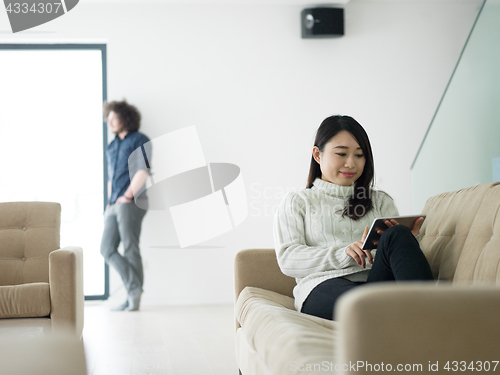 Image of multiethnic couple at home using tablet computers