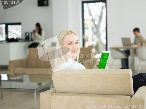 Image of young woman using tablet computer in front of fireplace