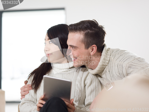 Image of multiethnic couple at home using tablet computers