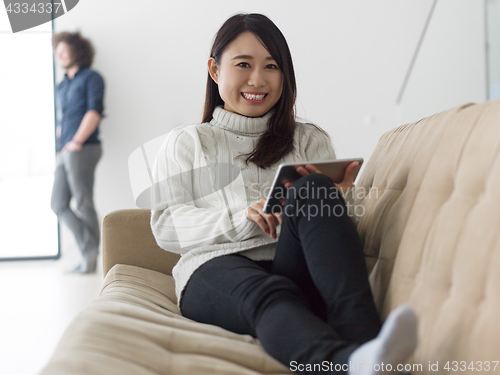 Image of multiethnic couple at home using tablet computers