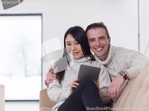 Image of multiethnic couple at home using tablet computers