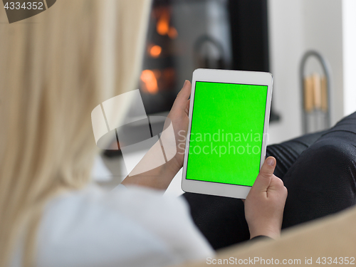 Image of young woman using tablet computer in front of fireplace