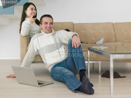 Image of multiethnic couple on the sofa watching television