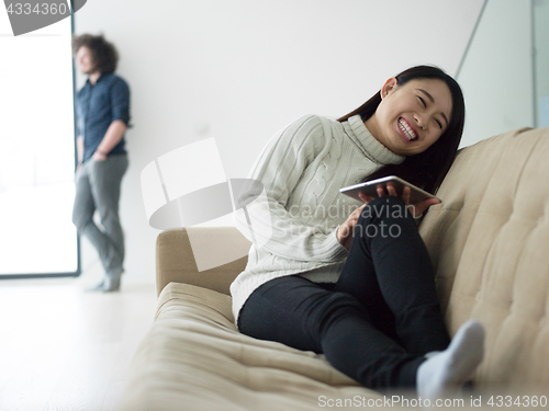 Image of multiethnic couple at home using tablet computers