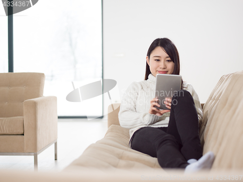 Image of asian woman using Digital Tablet on sofa