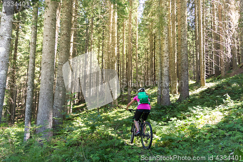 Image of Active sporty woman riding mountain bike on forest trail .