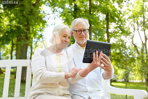 Image of happy senior couple with tablet pc in city park