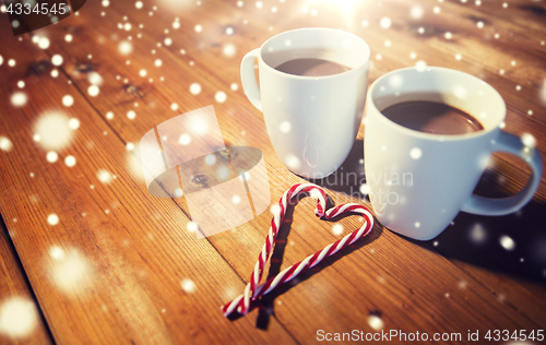 Image of christmas candy canes and cups on wooden table