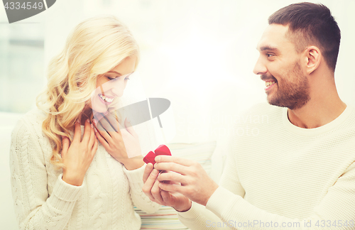 Image of happy man giving engagement ring to woman at home