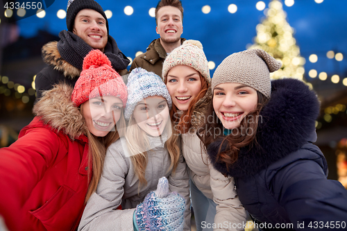 Image of happy friends taking selfie outdoors at christmas