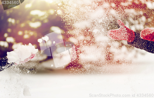 Image of happy friends playing with snow in winter