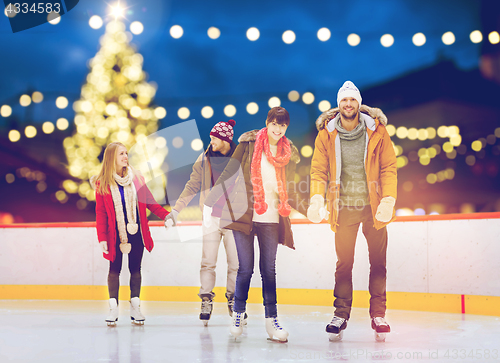 Image of happy friends on christmas skating rink