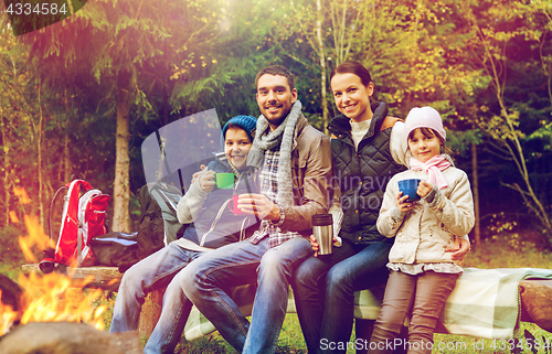 Image of happy family drinking hot tea at camp fire