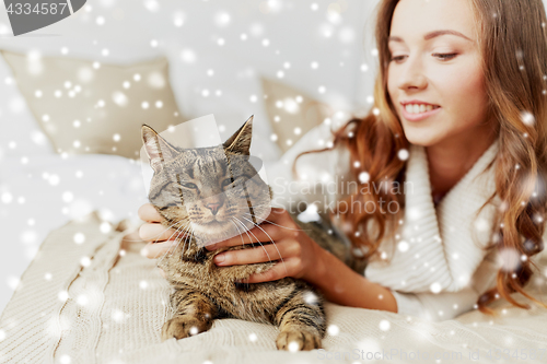 Image of happy young woman with cat lying in bed at home