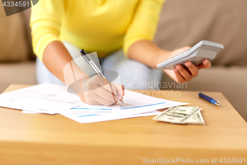 Image of woman with money, papers and calculator at home