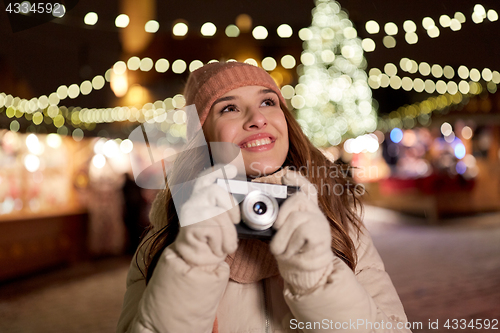 Image of happy young woman with camera at christmas market