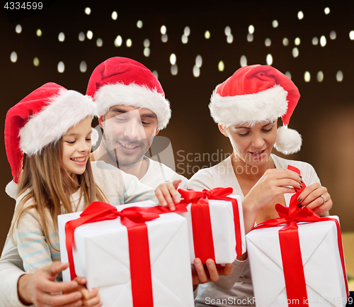 Image of happy family in santa hats with christmas gifts