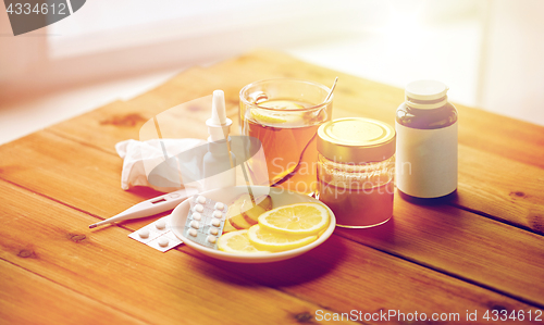 Image of drugs, thermometer, honey and cup of tea on wood