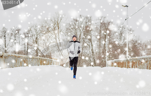 Image of man running along snow covered winter bridge road