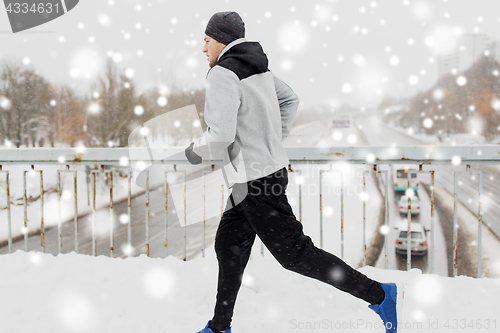 Image of man running along snow covered winter bridge road