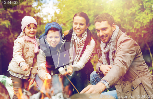 Image of happy family roasting marshmallow over campfire