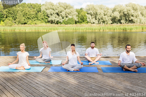 Image of people meditating in yoga lotus pose outdoors