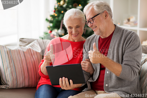 Image of happy senior couple with tablet pc at christmas