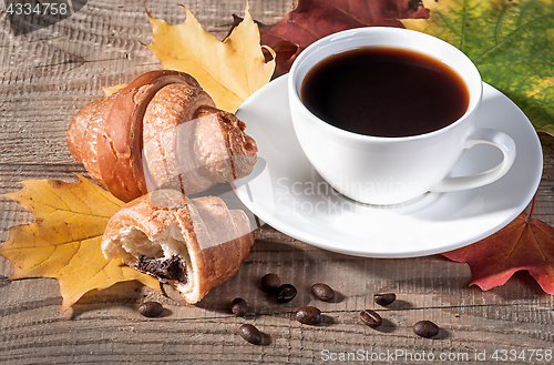 Image of Coffee with a croissant on a wooden table