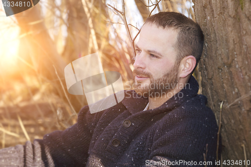 Image of a thoughtful bearded man in the forest sunset