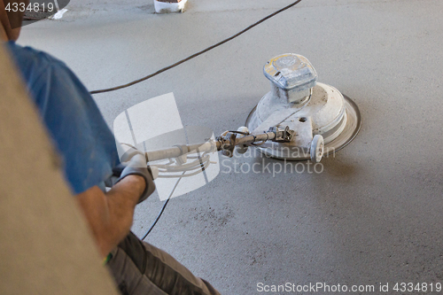 Image of Laborer polishing sand and cement screed floor.