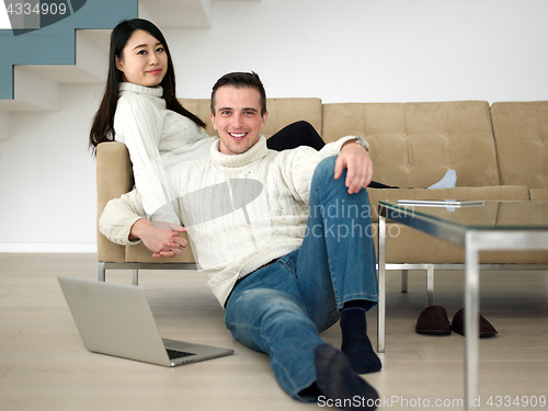 Image of happy multiethnic couple relaxing at home