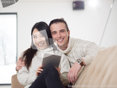 Image of multiethnic couple at home using tablet computers