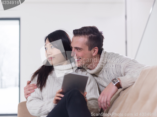 Image of multiethnic couple at home using tablet computers